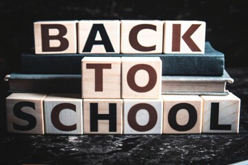 Back to school message spelled out with wooden letter blocks on stacked books
