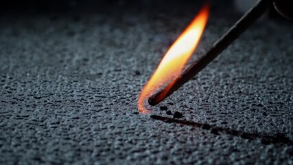 Scientist carefully burning wooden matchstick against dark asphalt, revealing glowing embers trailing across textured surface with intense heat and fiery combustion - Powered by Adobe