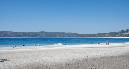 Beautiful Sandy Beach With Clear Blue Water and Mountains in the Distance on a Bright Sunny Day in Summer