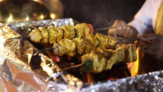 Paneer tikka roasting on grill with coal on skewers . Indian food