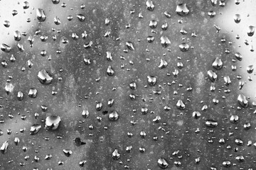 Drops of rain on the window with cloudy background.