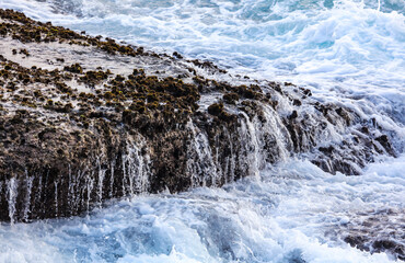 A rocky shoreline with a waterfall of water flowing down the rocks