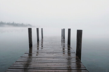 Naklejka premium Wooden Pier on Lake with Mist, Serene and Solitary Atmosphere (AI-generated)