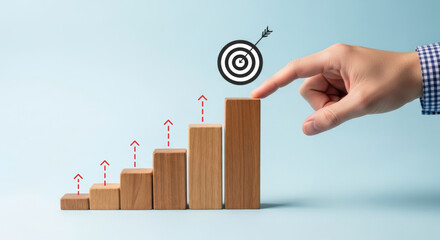 Hand pointing at target on top of wooden blocks arranged as a growing bar graph on blue background