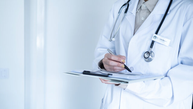 Close-up of doctor holding clipboard with patient documents, wearing stethoscope, representing professional healthcare and medical record review.