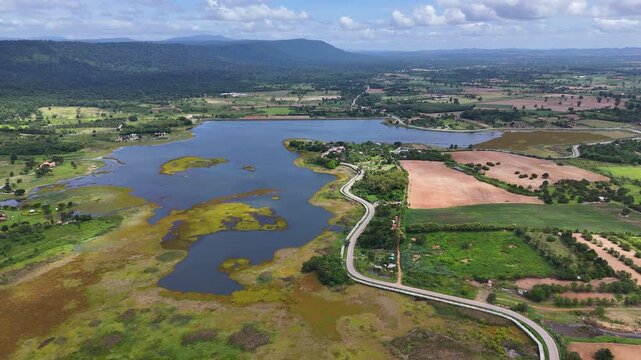 Drone footage of aerial view of Lam Phra Phloeng reservoir and surrounding farmland in Wang Nam Khiao, Nakhon ratchasima, Thailand. Scenic landscape of countryside with curved rural roads 