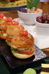 Restaurant food mini burger table with snack delicious dining. Catering service.Close-up of appetizer snacks mini burgers on a white plate. Ceremonial buffet. 