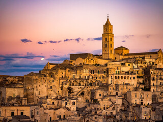 Obraz premium Sunset in the beautiful Sassi of Matera, with stone houses and streets, covered in warm golden light 
