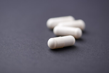 HMB capsules on dark background. Soft focus. Close up. Copy space.	
