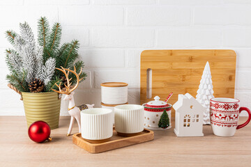 A beautiful set of ceramic mugs, dishes with a New Year pattern on a wooden tabletop decorated for the New Year and Christmas. Front view.