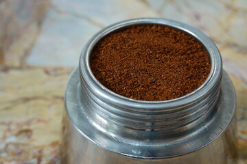 Freshly ground coffee is ready for brewing espresso in a classic Italian moka pot on a marble kitchen counter for a perfect morning start