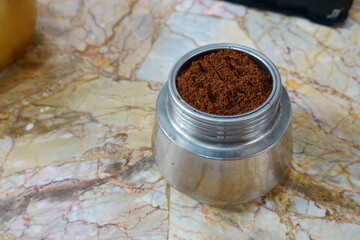 Freshly ground coffee is ready for brewing espresso in a classic Italian moka pot on a marble kitchen counter for a perfect morning start
