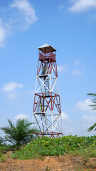 Tall metal observation tower amidst a bright blue sky and green vegetation, emphasizing the blend of nature and rural industrial infrastructure