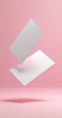 Two blank white business cards levitate against a pink backdrop