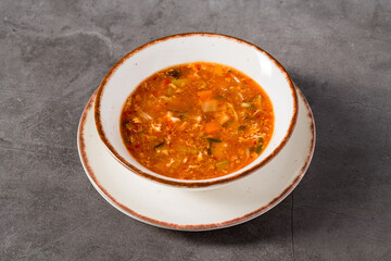 Hot and sour Asian soup with vegetables in white bowl