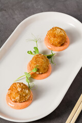 Three roasted chicken meatballs served with spicy dipping sauce and greens