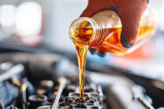 Pouring engine oil into a car engine during routine maintenance at a garage