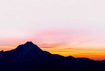 Obraz premium Serene mountain landscape at sunset, vibrant colors against a pale gray backdrop, minimal, panorama