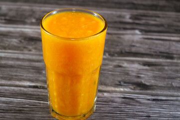A glass of fresh mango Juice with pieces of mango fruit, Mangoes, mango is an edible stone fruit produced by the tropical tree Mangifera indica, Fresh Juice summertime and holiday concept