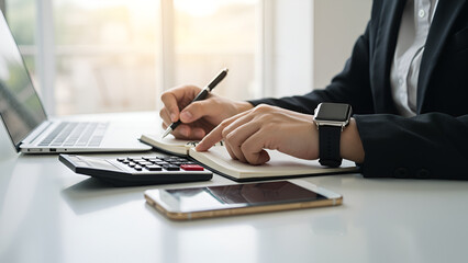 Person's Hands Calculating Finances and Writing Notes on Desk