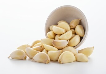 Peeled garlic cloves spilling out of a bowl isolated on white background
