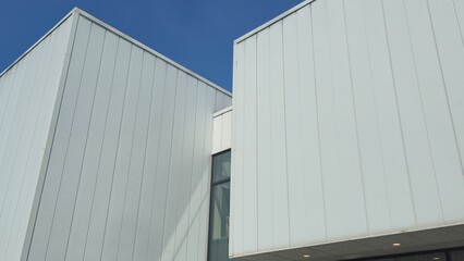 Modern architecture featuring clean white panel walls against bright blue sky background
