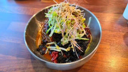 A vibrant bowl of Korean buckwheat noodles topped with fresh sprouts, crunchy cucumbers, seaweed flakes, and a spicy sauce blend that awakens the senses.