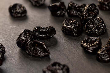 prunes from plums closeup, piled on a board made of stone dried plum , dried fruits on black slate