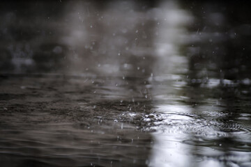 raining on the concrete walk way full with rain droplets splash ring bounce off the surface of water with reflected of white cloudy sky