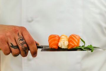 Creative sushi presentation with rolls balanced on chef’s knife, gourmet Japanese food concept