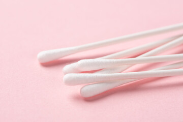 closeup of white cotton swabs on pink background.
