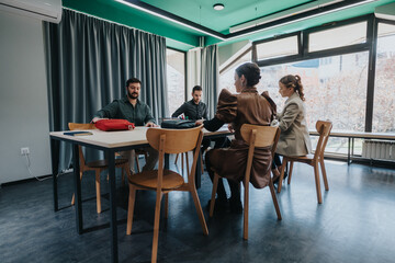 Group of colleagues collaborating and discussing ideas in a well-lit office environment. The atmosphere is productive, fostering creativity and teamwork, with participants seated around tables.