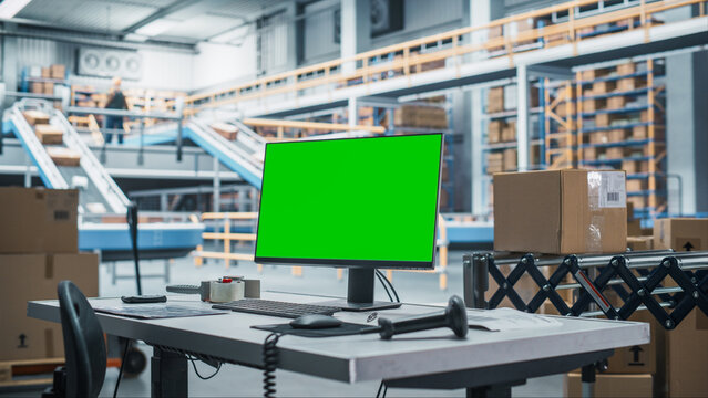 Empty Workplace Of Sorting Center Employee With Green Screen Chromakey Desktop Computer Monitor And Barcode Reader. Conveyor Belt With Online Orders Packaged In Cardboard Boxes Working On Background. - Powered by Adobe