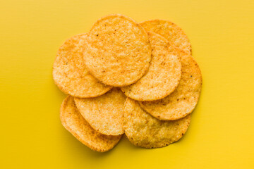 Crispy potato chips on yellow background. Top view.