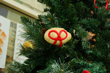 Christmas tree with croissant in bakery shop,ribbon croissant decor on christmas tree,cozy xmas decor at home or house,fir branch,tree with cones, mistletoe.