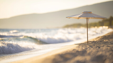 Fototapeta premium Sunny beach with gentle waves and a single umbrella under warm golden hour light.