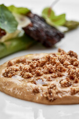 A fine dining dish featuring a savory paté topped with crunchy elements, served with a delicate salad of asparagus and microgreens on a white plate.