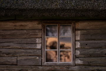 Old wooden log house window background. Rustic Log cabin and window with a reflection of sunrise. 