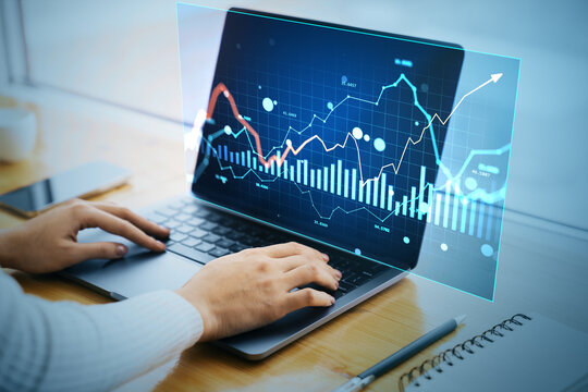 Businessperson analyzing digital financial charts on laptop with futuristic data hologram interface in modern workspace background concept. - Powered by Adobe