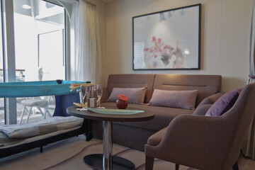 Luxurious suite stateroom cabin room onboard luxury yacht cruise ship cruiseship liner with bedroom and living area in purple and creme with wood in modern Art Deco interior design