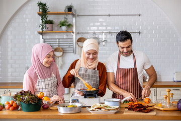 Family of happy Arab muslim sibling helping each other to food preparation in the kitchen for cooking tasty halal meal at home in Middle east and Persian cuisine culture concept