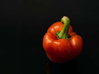 Fresh Orange Bell Pepper on Black Background, Closeup, with Water Droplets.
