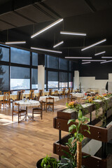 Restaurant interior with large sunlit windows and wooden chairs