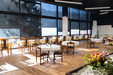 Restaurant interior with large sunlit windows and wooden chairs
