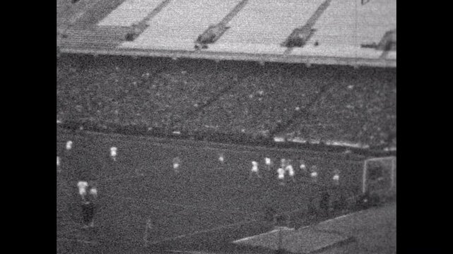 Archive film, football match, players running across field, wide view from above. Abstract match sports league in stadium. Professional event competition. Vintage old video. Archival retro 1960s