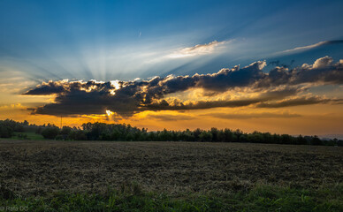 Sonnenuntergang über einem abgeernteten Feld in ländlicher Landschaft