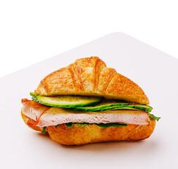 Savory turkey sandwich on a flaky croissant with fresh vegetables