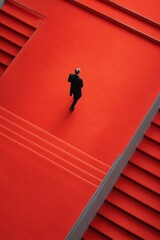 Una figura solitaria avanza por una escalera roja, simbolizando el progreso y la determinación.