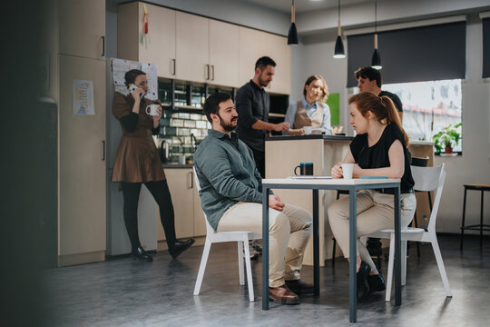 A group of coworkers collaborates in a shared office kitchen space, fostering ideas and discussions.