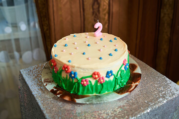 A birthday cake in pastel and green tones during a child's birthday celebration
